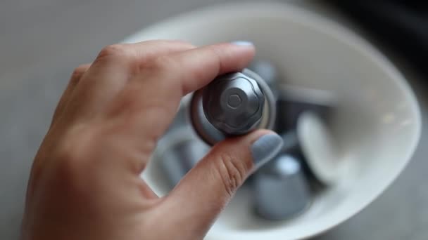 Persona prende una piccola capsula d'argento per una macchina da caffè automatica da una piastra bianca in cucina - Filmati, video