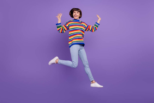 Photo of glad cheerful lady jump move enjoy flight have fun wear sweater jeans shoes isolated purple color background - Foto, Imagem