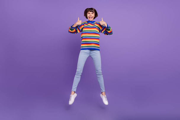 Photo of cute lady jump raise thumbs up give feedback wear striped sweater jeans shoes isolated violet color background - Φωτογραφία, εικόνα