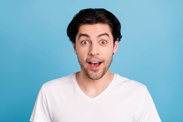 Photo of amazed surprised funky guy omg sale reaction open mouth wear white t-shirt isolated blue color background - Foto, Bild