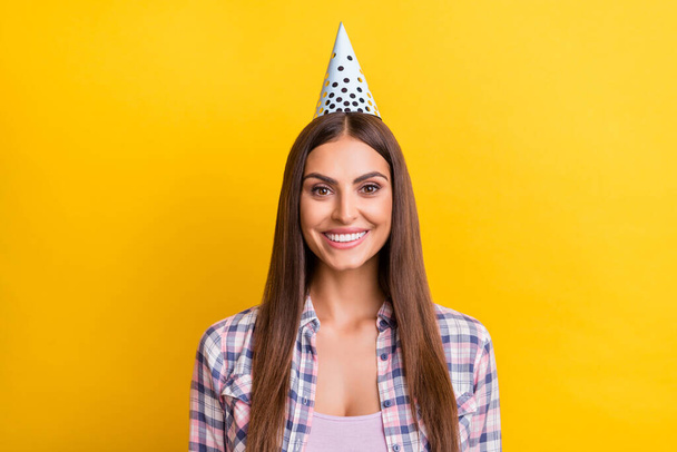 Photo of young woman happy positive smile wear birthday cone celebration isolated over yellow color background - Foto, Imagen