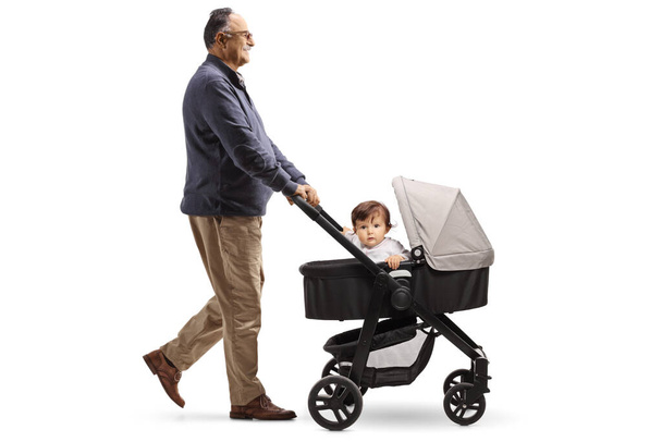 Full length profile shot of a grandpa walking a baby in a stroller isolated on white background - Fotografie, Obrázek