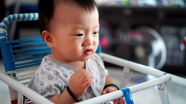 ondeugende baby jongen glimlach terwijl eten pap zitten op kinderstoel - Video