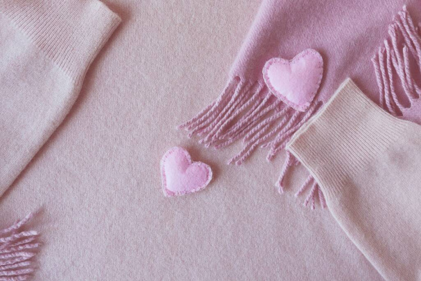 войлочные сердца на розовую кашемировую одежду, вид сверху, концепция Дня Святого Валентина, теплые уютные продукты - Фото, изображение