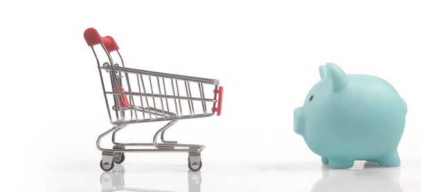 Toy shopping cart and Piggy bank. Consumer society trend - Foto, imagen