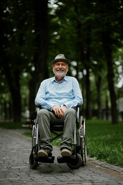 Uomo adulto disabile in sedia a rotelle tiene foglio di carta - Foto, immagini