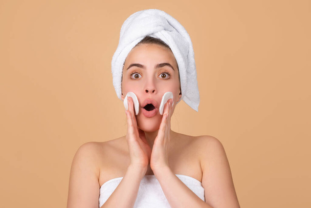 Excited beautiful woman with clean skin. Girl beauty face care. Facial treatment. Spa skin care, beauty woman wearing hair towel after beauty treatment. Beautiful perfect skin, isolated beige. - Foto, Bild