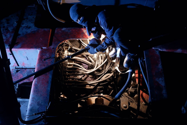 De monteur repareert de motor. 's Nachts - Foto, afbeelding