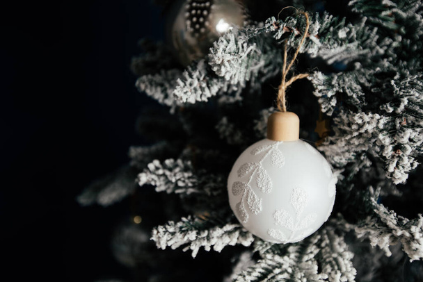 Beautiful Christmas bauble with feathers on a snowy tree against blue background.  - Photo, Image