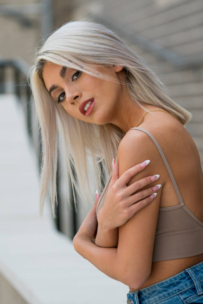 A gorgeous blonde model poses outdoors in an urban environment - Photo, image