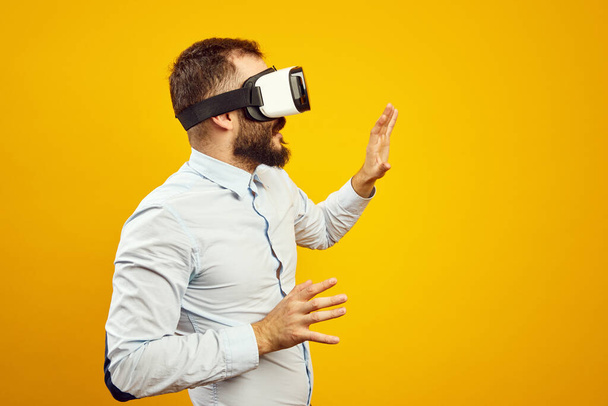 Вид збоку молодого чоловіка в шоломі віртуальної реальності, який торкається повітря
 - Фото, зображення