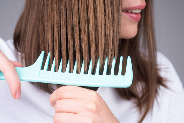Close up brushing hair with comb. Combing long hair with hairbrush. - Foto, Imagen