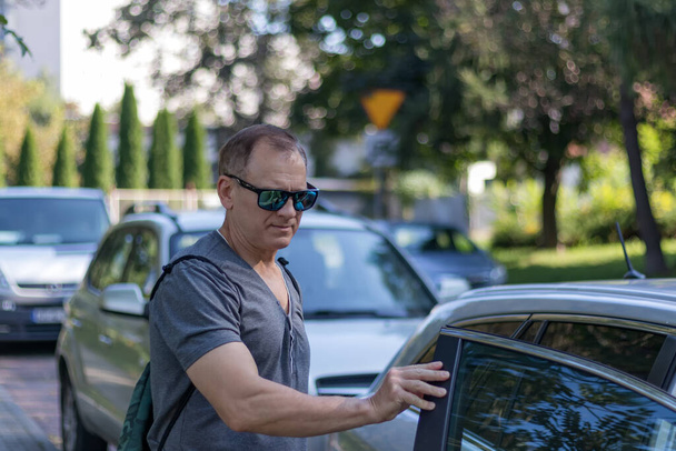 jóképű érett férfi 50 éves, áll az autó mellett, férfi portré az utcán - Fotó, kép