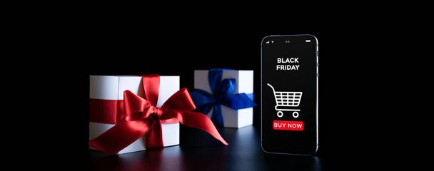Shopping buio. App online Internet sul cellulare, confezione regalo bianca con nastro rosso isolato su sfondo nero nel concetto di Venerdì nero. Shopping buio - Foto, immagini
