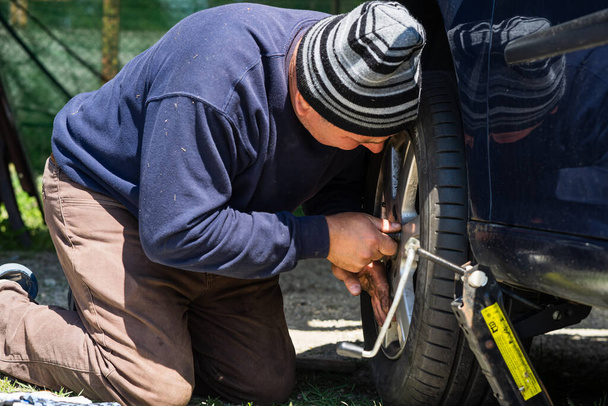 Close up of mechanic changing wheel on car with hand tool in Romania, Bucharest, 2022 - Foto, imagen