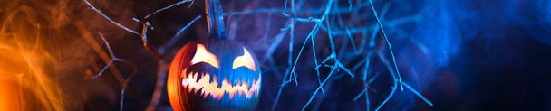 Spooky Halloween jack o lantern pumpkin with carved scary face glowing and billowing smoke in the night. - Photo, Image