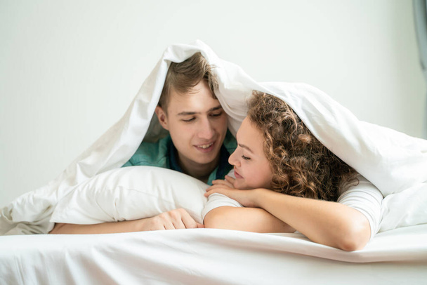 Young happy caucasian couple morning wake up lying together in bed happy people - Photo, Image