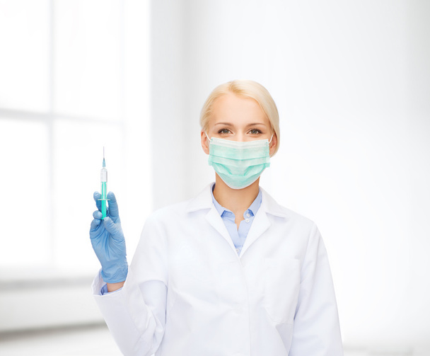 doctor in mask holding syringe with injection - Foto, Bild