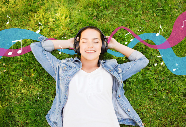 smiling young girl in headphones lying on grass - Fotoğraf, Görsel