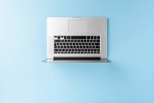 Сучасний ноутбук на синьому фоні з копіювальним простором. Офісна стільниця. Вид зверху
 - Фото, зображення