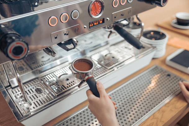 Female barista using professional coffee machine in cafeteria - 写真・画像