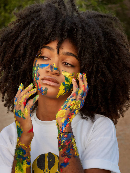 Little girl enjoying nature with her face painted in different colors        - Photo, Image