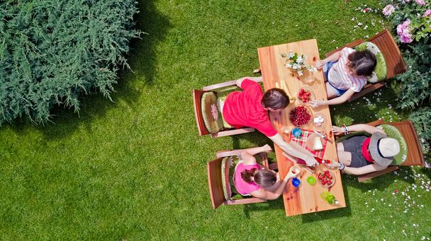 Family and friends eating together outdoors on summer garden party. Aerial view of table with food and drinks from above. Leisure, holidays and picnic concept - Valokuva, kuva