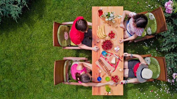 Family and friends eating together outdoors on summer garden party. Aerial view of table with food and drinks from above. Leisure, holidays and picnic concept - Valokuva, kuva