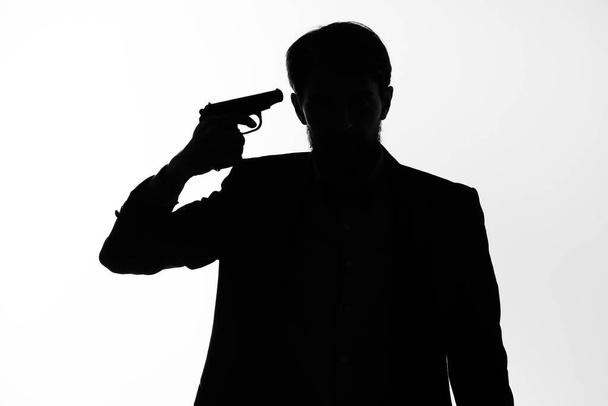 A férfi öltönyben, egy titkos ügynök fegyverrel a kezében, egy bűnügyi pózstúdió kezében. - Fotó, kép