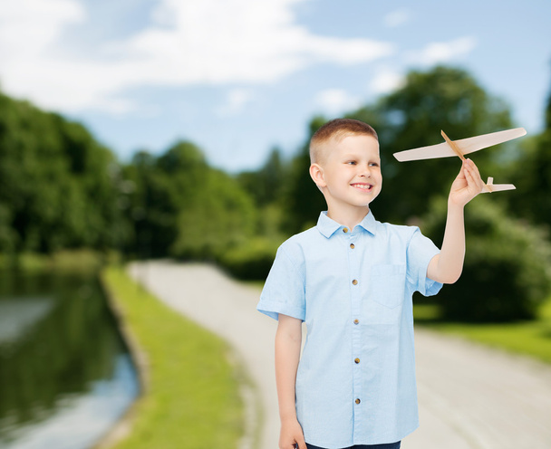 smiling little boy holding a wooden airplane model - Фото, изображение