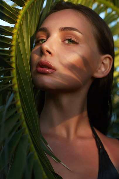 Piękna letnia dziewczyna o zachodzie słońca. młoda seksowna kobieta w bikini pod palmą. Portret piękności - Zdjęcie, obraz