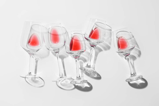 Stilvolle Komposition von Gläsern mit übrig gebliebenem Rotwein auf hellem Hintergrund - Foto, Bild