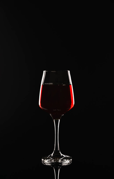 Glas heerlijke rode wijn op zwarte achtergrond - Foto, afbeelding