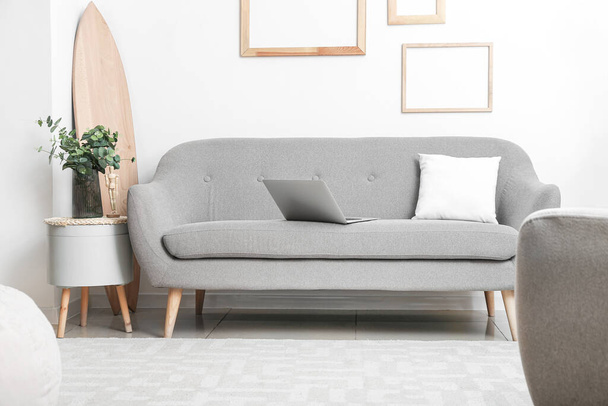 Harmaa moderni sohva ja lasi maljakko eukalyptus pöydällä lähellä valoa seinään - Valokuva, kuva