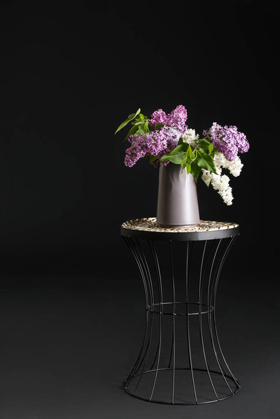 Lilac flowers in stylish vase on table on dark background - Photo, Image