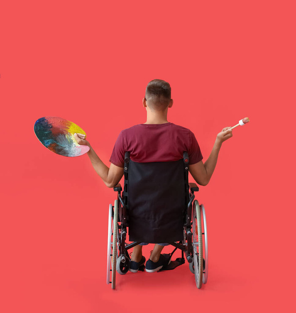 Mladý muž umělec na invalidním vozíku na barevném pozadí - Fotografie, Obrázek