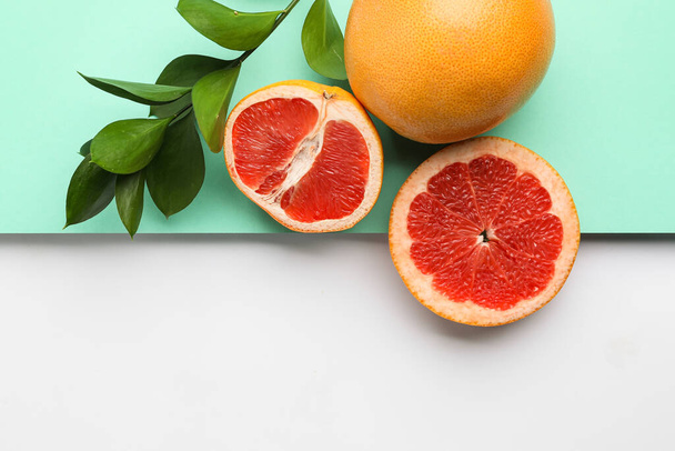 Ripe grapefruits and plant branch on color background - Foto, imagen