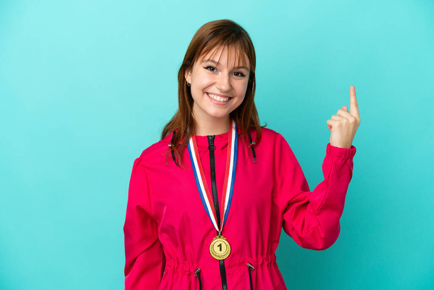 Zrzka dívka s medailemi izolované o modré pozadí ukazuje ukazováčkem skvělý nápad - Fotografie, Obrázek
