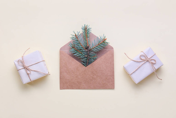 Envelope with fir tree branches and Christmas gift boxes on light background - Foto, immagini
