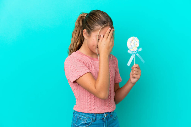 Little Caucasian girl holding a lollipop isolated on blue background laughing - Photo, Image