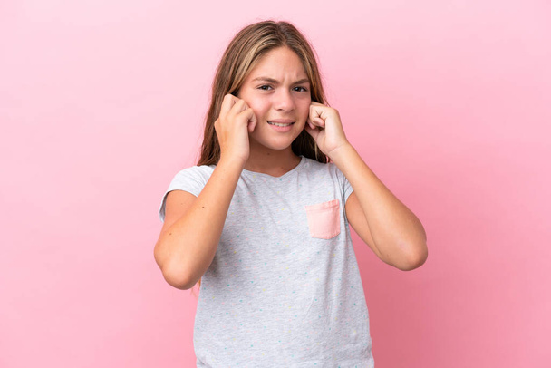 Little caucasian girl isolated on pink background frustrated and covering ears - 写真・画像