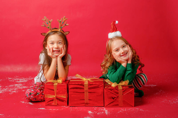 niñas en pijama con regalos sobre un fondo rojo  - Foto, imagen