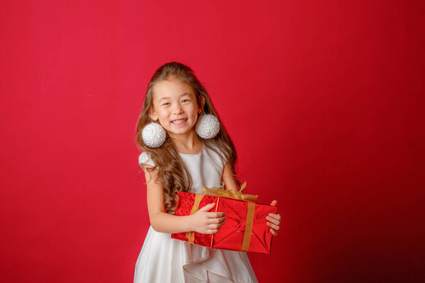 Asian little girl holding gift on red background - Φωτογραφία, εικόνα