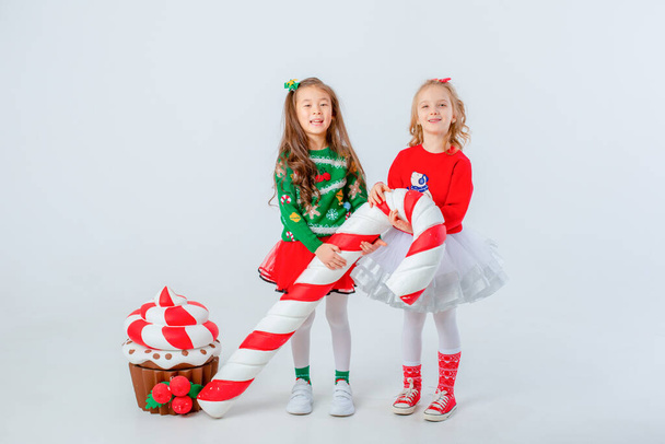 deux petites filles avec cupcake et grand caramel isolé sur fond blanc - Photo, image