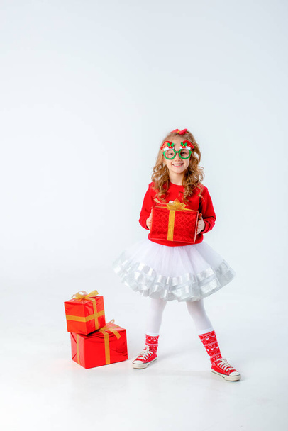 little girl in carnival christmas glasses holding gift on white background - Фото, изображение