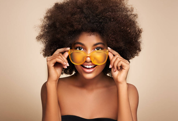 Beauty portrait of African American girl in colored sunglasses. Beautiful black woman. Cosmetics, makeup and fashion - Fotografie, Obrázek