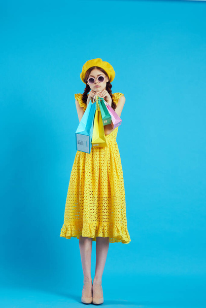 cheerful woman yellow dress shopping fun blue background - Фото, изображение