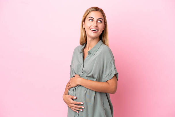 Giovane donna uruguaiana isolata su sfondo blu incinta e felice - Foto, immagini