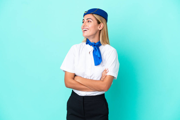 Airplane stewardess Uruguayan woman isolated on blue background happy and smiling - Photo, Image