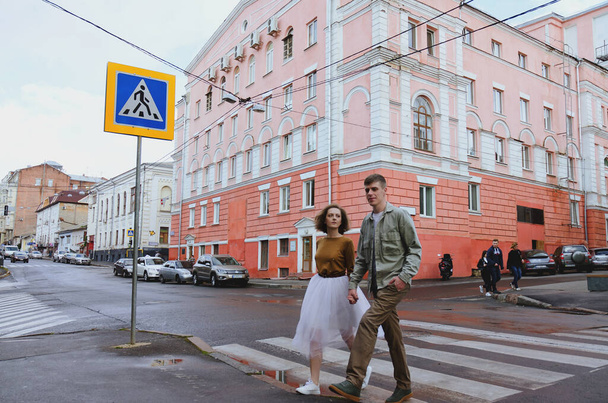 Kharkiv, Ukraine. 09.19.2021. Love story of stylish funny couple: young man in a t-shirt. And a cute young woman in wedding white skirt and yellow sweater. Family holiday and togetherness, date. - Photo, Image